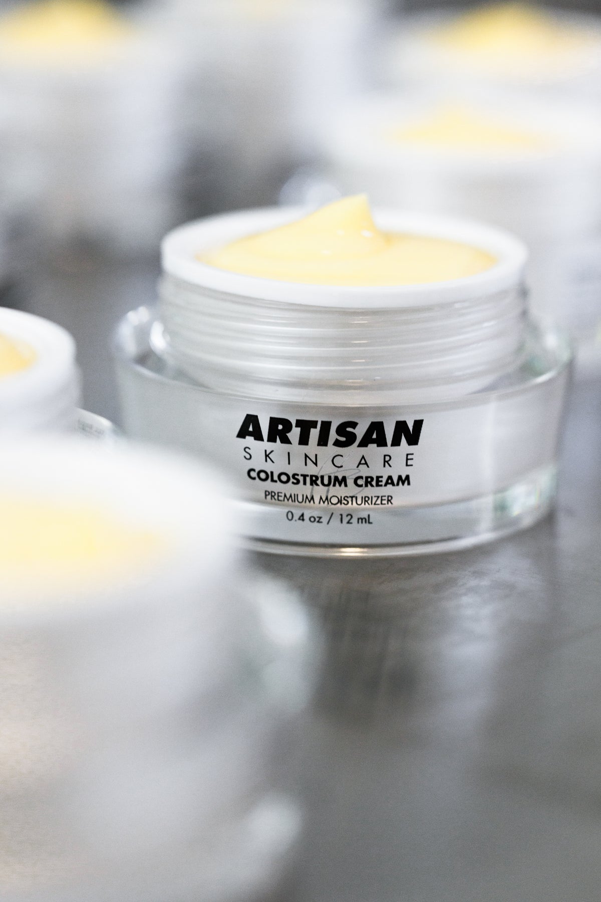 An open jar of Colostrum Cream photographed close up, the surface of the cream visible.